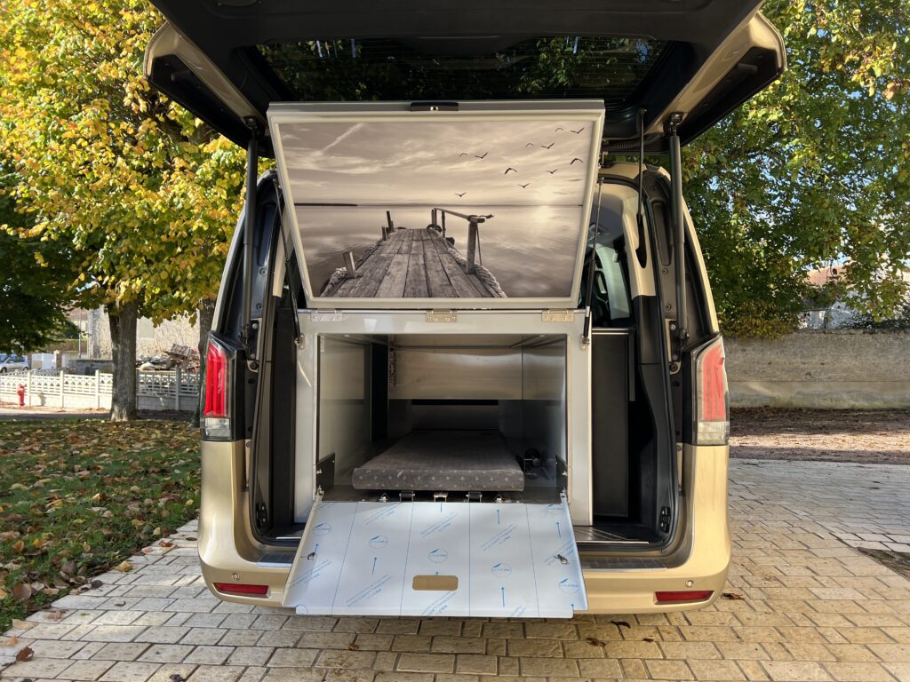 ménagement premium Iris de la Maison Collet sur châssis Mercedes, avec caisson sanitaire et panneau décoratif relevable (motif ponton).